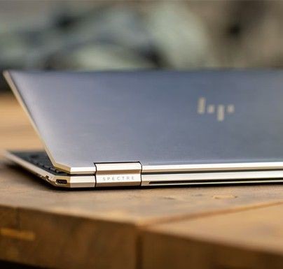 Laptop HP Spectre semichiuso su scrivania in legno